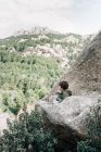 Маленька дитина в пальто, що йде скелястим схилом пагорба, досліджує природу — стокове фото