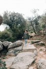 Petit enfant curieux en manteau descendant une colline rocheuse à la découverte de la nature — Photo de stock