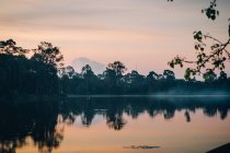 Paisagem de água tranquila do lago com névoa acima em horas do nascer do sol, Tailândia — Fotografia de Stock