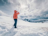 Persona irriconoscibile in piedi nella neve circondata da boschi e montagne — Foto stock