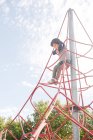 Entspanntes Kind hängt an Seil-Kletternetz auf Spielplatz in hellem Licht — Stockfoto