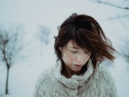 Портрет задумчивой привлекательной брюнетки в белом свитере на фоне снежной зоны — стоковое фото