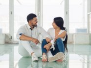 Young handsome man embracing attractive smiling woman sitting on the floor — Stock Photo
