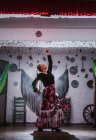 Жіноча танцівниця в костюмі фламенко стоїть в танцювальній позі в етнічній кімнаті з антикварними предметами на стіні — стокове фото
