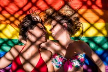 Lésbicas casal deitado na bandeira do arco-íris — Fotografia de Stock