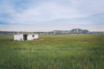 Paesaggio di bianco casa solitaria in infiniti campi verdi su sfondo di colline e cielo blu — Foto stock