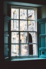 Vista a través de un viejo marco de ventana con un edificio de piedra envejecido detrás en luz natural suave, Escocia - foto de stock