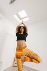 African American attractive young woman performing yoga posture with stretched arms on mat in light room — Stock Photo