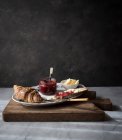 Croissant crocante crocante com torrada, manteiga e marmelada de morango servido na placa em tábua de madeira — Fotografia de Stock
