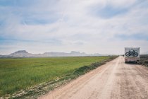 Белый прицеп на пустой дороге между зелеными полями — стоковое фото