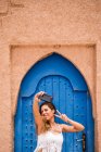 Jovem alegre vestindo top branco com biquíni tirando selfie com telefone contra a porta oriental azul na parede de pedra, Marrocos — Fotografia de Stock
