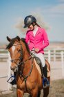 Vue rapprochée du jockey adolescent à cheval sur un hippodrome par une journée ensoleillée — Photo de stock