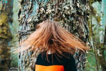 Beautiful young woman in casual sweatshirt waving with ginger colored hair against old tree, Scotland — Stock Photo