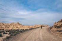 Чоловік ходить по дорозі в пустельних пагорбах — стокове фото