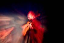 Uomo ispanico che suona la chitarra acustica durante la performance di flamenco sul palco buio — Foto stock