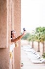 Cheerful woman using mobile phone to take a selfie near desert landscape standing on stone balcony, Morocco — Stock Photo