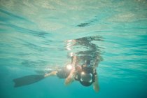Buceador deportivo tomando fotografías submarinas en aguas turquesas serenas - foto de stock