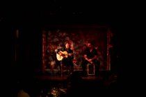 Homens hispânicos tocando percussão e guitarra acústica durante a performance do flamenco no palco escuro — Fotografia de Stock