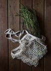 De cima de saco de corda branca com grande pacote de espargos verdes frescos na mesa de madeira — Fotografia de Stock