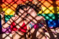 Lesbian couple lying on rainbow flag — Stock Photo
