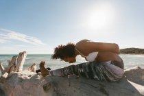African American woman doing titibasana yoga posture on beach — Stock Photo