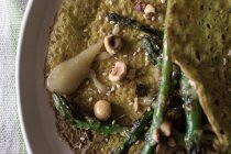 Closeup of oat crepe with asparagus and tahini paste served on white plate on rustic background — Stock Photo