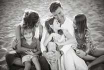 Adulto homem amoroso e mulher com filhos e filhas alegres sentados juntos olhando um para o outro, foto em preto e branco — Fotografia de Stock