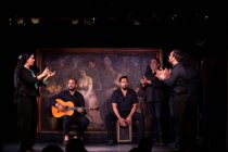 Uomini ispanici che suonano percussioni e chitarra acustica durante le esibizioni di flamenco sul palco buio — Foto stock