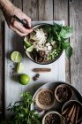Human hand with chopsticks and Pho soup with noodles on marble board on wooden table with spices — Stock Photo