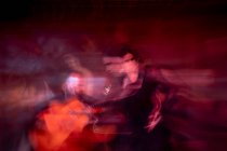 Woman in black costume dancing flamenco near Hispanic male musicians during performance against painting on dark stage — Stock Photo