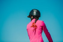 Blick zurück auf anonyme Jockeyspielerinnen, die an einem sonnigen Tag auf der Rennbahn vor blauem Himmel reiten — Stockfoto