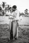 Black and white of adult loving man and woman embracing and kissing on beach — Stock Photo