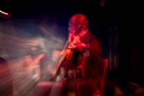 Uomo ispanico che suona la chitarra acustica durante la performance di flamenco sul palco buio — Foto stock