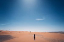 Bärtiger Mann im Cowboykostüm schaut weg, während er in der Wüste vor blauem Himmel steht — Stockfoto