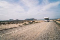 Белый трейлер едет по пустой дороге вдоль пустыни — стоковое фото