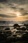 Vue pittoresque des pierres humides sur le bord de mer calme contre le ciel couchant — Photo de stock
