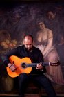 Лысый бородатый парень, играющий на акустической гитаре во время выступления фламенко — стоковое фото