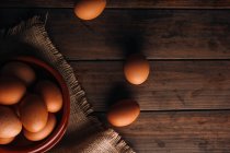 Курячі яйця з мискою і мішковиною на дерев'яному столі — стокове фото