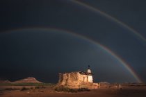 Einsames altes Haus in der Wüste und Regenbogen am stürmischen Himmel — Stockfoto