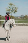Déterminé fille jockey sur l'équitation sur hippodrome par une journée ensoleillée — Photo de stock