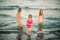Gruppo di ragazzini con due sorelle che giocano in acque poco profonde sulla costa — Foto stock