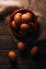 Uova di pollo con ciotola e sacco sul tavolo di legno — Foto stock