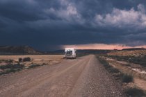 Remorque debout sur le côté de la route vide sous un ciel orageux dramatique — Photo de stock