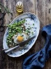 Piatto servito con piselli verdi saltati e uovo fritto sul tavolo di legno — Foto stock