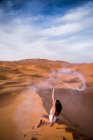 Allegro bruna elegante braccio alzato con fumoso fuoco d'artificio in fiamme seduto nel deserto del Marocco — Foto stock