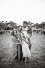 Adulto amante hombre y mujer con hijo e hijas de pie juntos en la playa en la espalda iluminado sonriendo a la cámara, foto en blanco y negro - foto de stock