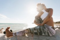 Donna afroamericana che fa titibasana yoga postura sulla spiaggia soleggiata — Foto stock