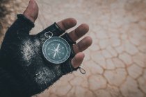 Nahaufnahme der Hand in schwarzem fingerlosen Handschuh mit Kompass auf Wüstenplatz — Stockfoto