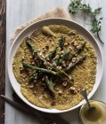Closeup of oat crepe with asparagus and tahini paste served on white plate on rustic background — Stock Photo