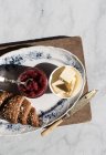 Teller mit knusprigem Croissant und Butter und Erdbeermarmelade auf Holzbrett serviert — Stockfoto